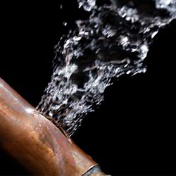 A bursting copper pipe in Du Bois, with water gushing out.