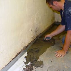 A basement waterproofer installing a perimeter drain system in Emporium