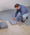 Contractors installing basement subfloor tiles and matting on a concrete basement floor in Tyrone, Pennsylvania