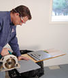 installing a waterproof vapor barrier on a basement floor to prepare for basement carpeting in a Du Bois home